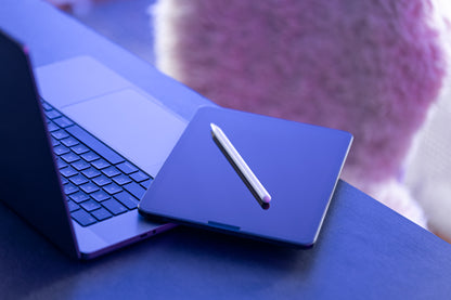 Laptop with stylus on a blue surface, blurred background